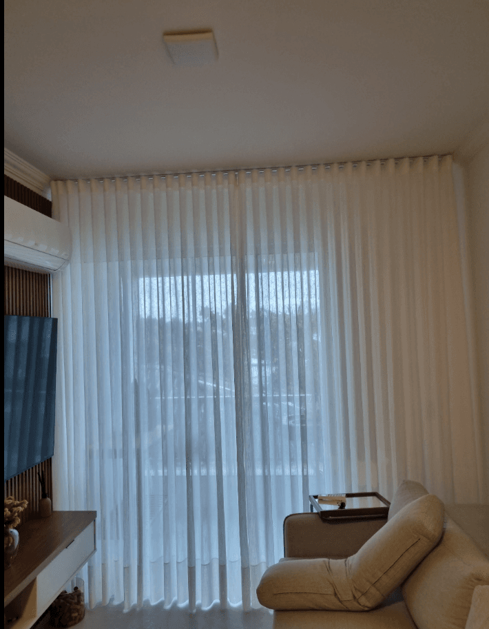 Sala com cortinas de linho filtrando luz natural de forma suave e elegante